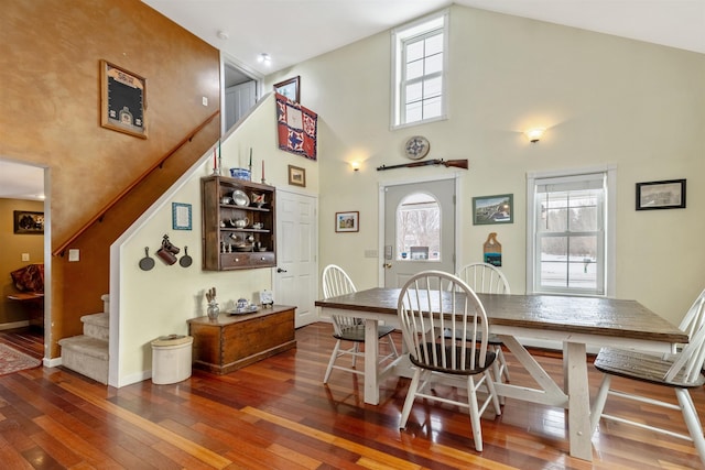 dining room featuring dark wood-type flooring, high vaulted ceiling, and plenty of natural light