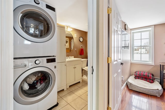 washroom with stacked washer / dryer and light tile patterned floors