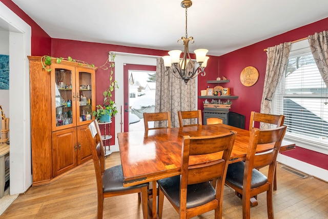 dining room with plenty of natural light, light wood-type flooring, and an inviting chandelier