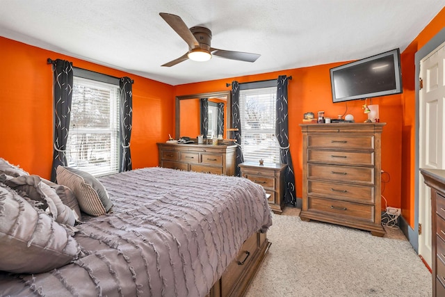 bedroom featuring multiple windows, ceiling fan, and light colored carpet