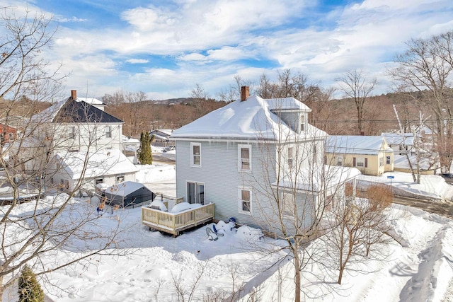 snow covered back of property with a wooden deck