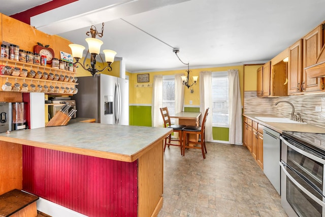 kitchen with a notable chandelier, stainless steel appliances, decorative light fixtures, sink, and kitchen peninsula