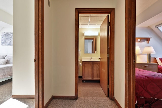 corridor with sink, a paneled ceiling, and carpet