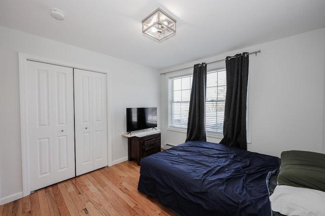 bedroom featuring light wood-type flooring, a closet, and baseboard heating