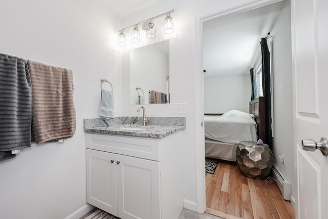 bathroom with hardwood / wood-style floors, vanity, and a baseboard radiator