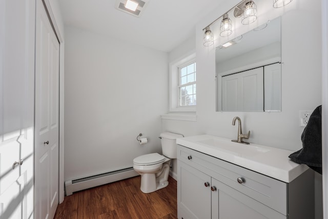 bathroom with toilet, baseboard heating, vanity, and hardwood / wood-style flooring