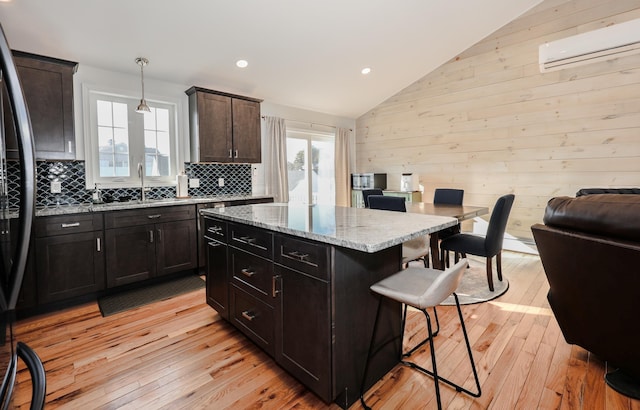 kitchen featuring hanging light fixtures, a kitchen island, sink, a healthy amount of sunlight, and a kitchen breakfast bar