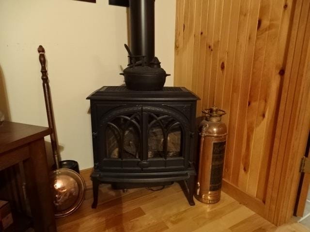 room details with wood finished floors, a wood stove, and wooden walls