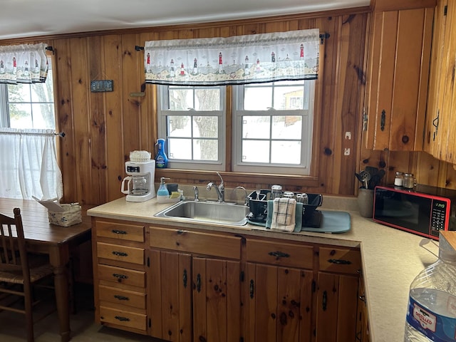 kitchen with brown cabinets, light countertops, a sink, and wooden walls