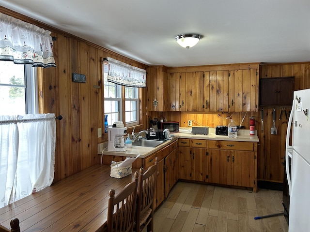 kitchen featuring brown cabinetry, light countertops, a sink, and freestanding refrigerator