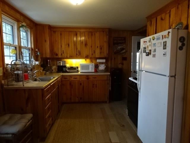 kitchen with brown cabinetry, white appliances, and a sink