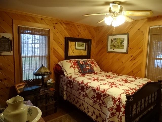 bedroom featuring a ceiling fan and wood walls