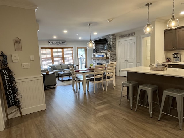 kitchen with dark wood-type flooring, hanging light fixtures, crown molding, and a breakfast bar area