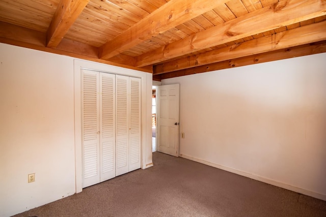 unfurnished bedroom featuring wooden ceiling, beamed ceiling, carpet flooring, and a closet