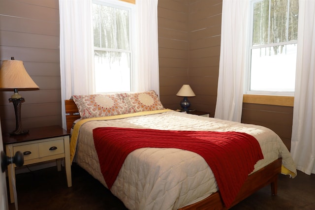 bedroom with multiple windows and wooden walls