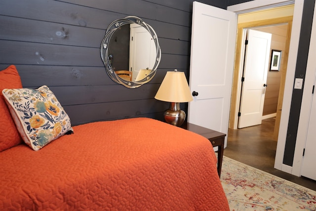 bedroom featuring concrete flooring and wooden walls