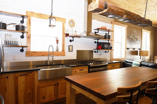 kitchen featuring sink, butcher block counters, range hood, stainless steel range with gas cooktop, and hanging light fixtures