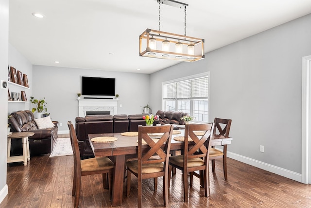 dining space featuring dark wood-type flooring and a fireplace