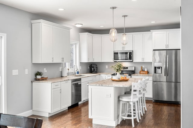 kitchen featuring sink, pendant lighting, a kitchen island, stainless steel appliances, and white cabinets