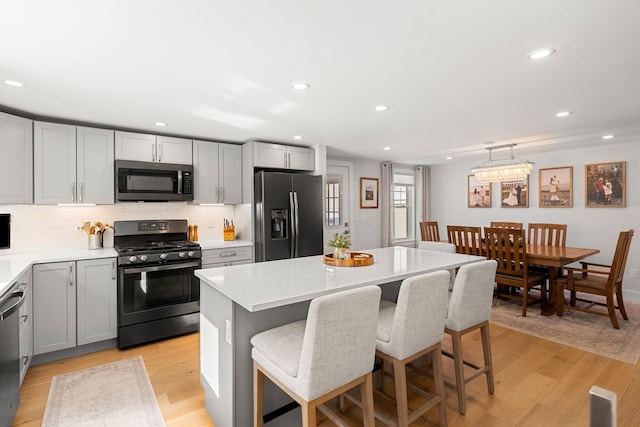 kitchen featuring a kitchen island, stainless steel appliances, gray cabinetry, and decorative light fixtures