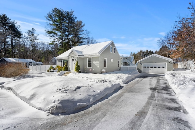 snow covered property with a garage and an outdoor structure