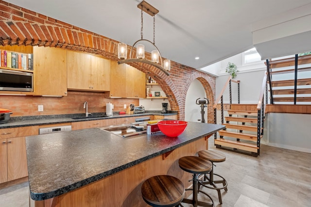 kitchen featuring a center island, decorative light fixtures, cooktop, sink, and decorative backsplash