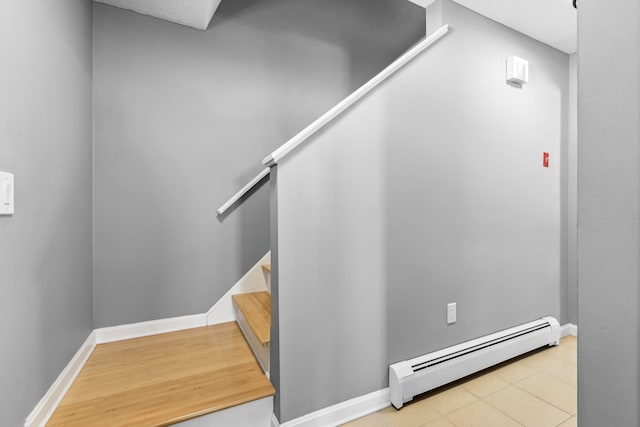 staircase featuring a baseboard heating unit and wood-type flooring