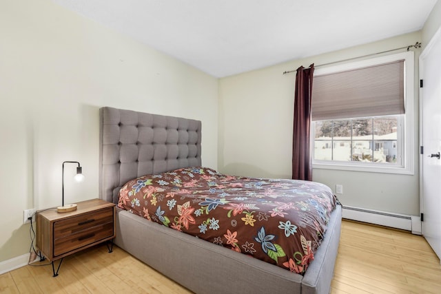 bedroom featuring baseboard heating and light hardwood / wood-style flooring