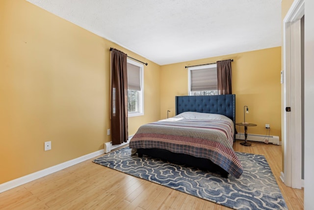 bedroom featuring wood-type flooring and a baseboard heating unit