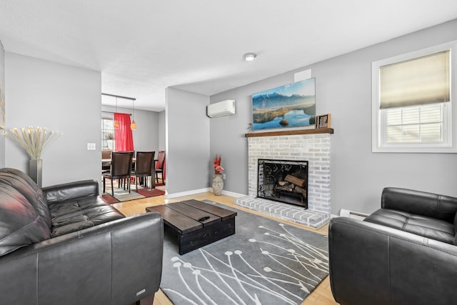 living room with a brick fireplace, light wood-type flooring, baseboard heating, and a wall mounted AC