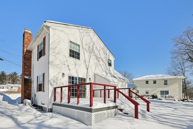 snow covered back of property with a wooden deck