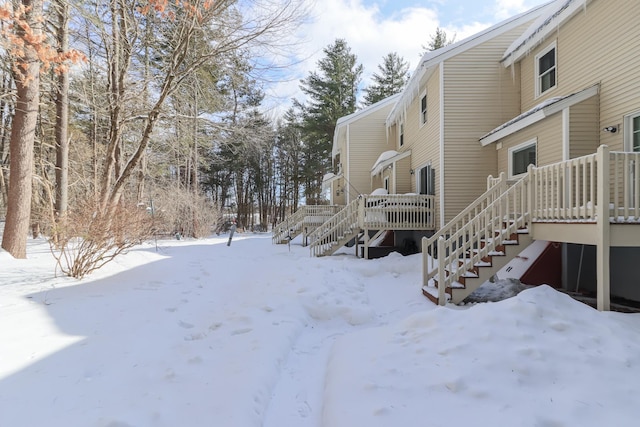 snowy yard with a wooden deck and stairs