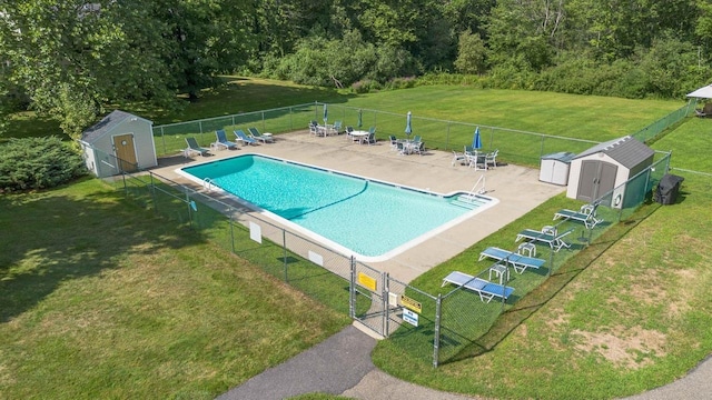 pool with a yard, a shed, fence, and an outdoor structure