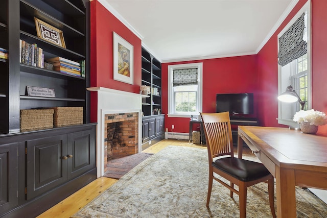 office space with a baseboard radiator, crown molding, a fireplace, light wood-type flooring, and built in features