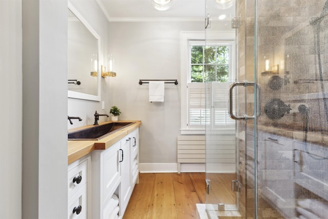 bathroom featuring an enclosed shower, vanity, hardwood / wood-style floors, and crown molding