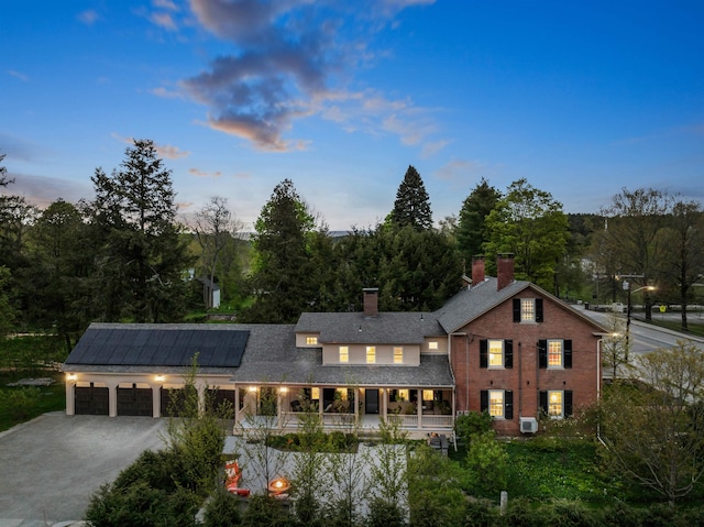 view of front of house featuring covered porch, solar panels, and a garage