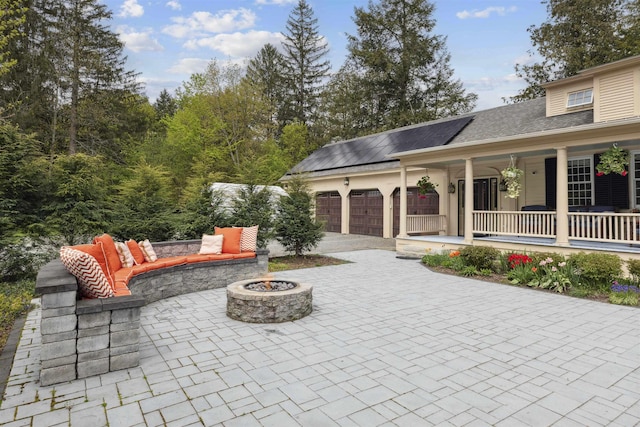 view of patio with a porch, a garage, and a fire pit