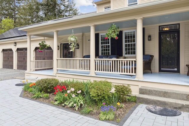 view of exterior entry with a garage and a porch