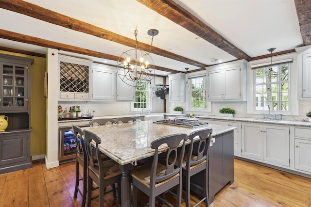 kitchen featuring light stone counters, a center island, pendant lighting, beamed ceiling, and a kitchen breakfast bar