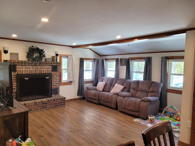 living room with crown molding, a wealth of natural light, wood-type flooring, and a fireplace