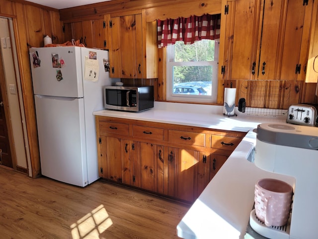 kitchen with wood walls, white refrigerator, and light hardwood / wood-style flooring