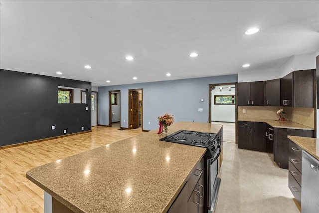 kitchen featuring dark brown cabinetry, light hardwood / wood-style flooring, a kitchen island, electric stove, and light stone counters