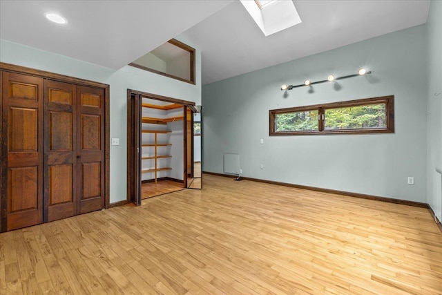 unfurnished bedroom featuring light wood-type flooring and vaulted ceiling with skylight