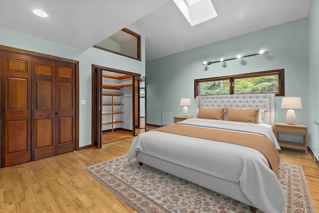 bedroom featuring lofted ceiling with skylight and light hardwood / wood-style floors