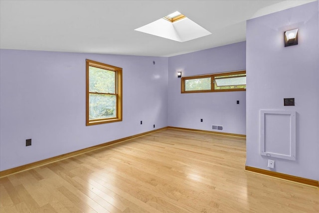 spare room featuring light wood-type flooring, a skylight, and plenty of natural light