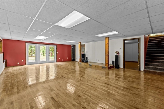 unfurnished living room featuring french doors, hardwood / wood-style floors, and a drop ceiling