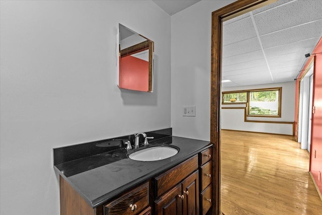 bathroom with a paneled ceiling, vanity, and hardwood / wood-style floors