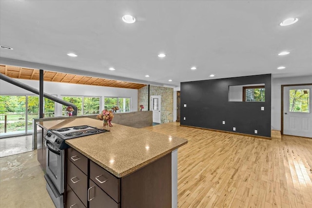 kitchen featuring dark brown cabinetry, light hardwood / wood-style flooring, range with electric stovetop, vaulted ceiling, and light stone counters