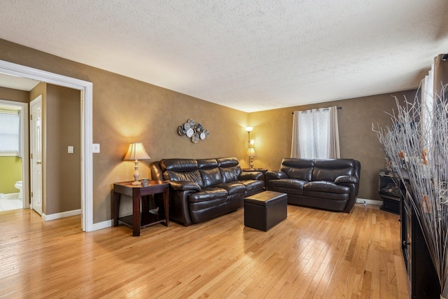 living area featuring a textured ceiling, baseboards, and wood finished floors