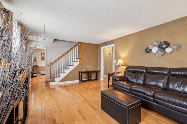 living area with a textured ceiling, stairway, wood finished floors, and baseboards